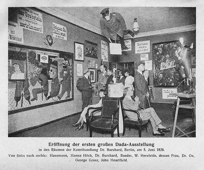 Grand opening of the first Dada exhibition: International Dada Fair, Berlin, 5 June 1920. The central figure hanging from the ceiling was an effigy of a German officer with a pig's head. From left to right: Raoul Hausmann, Hannah Höch (sitting), Otto Burchard, Johannes Baader, Wieland Herzfelde, Margarete Herzfelde, Dr. Oz (Otto Schmalhausen), George Grosz and John Heartfield.