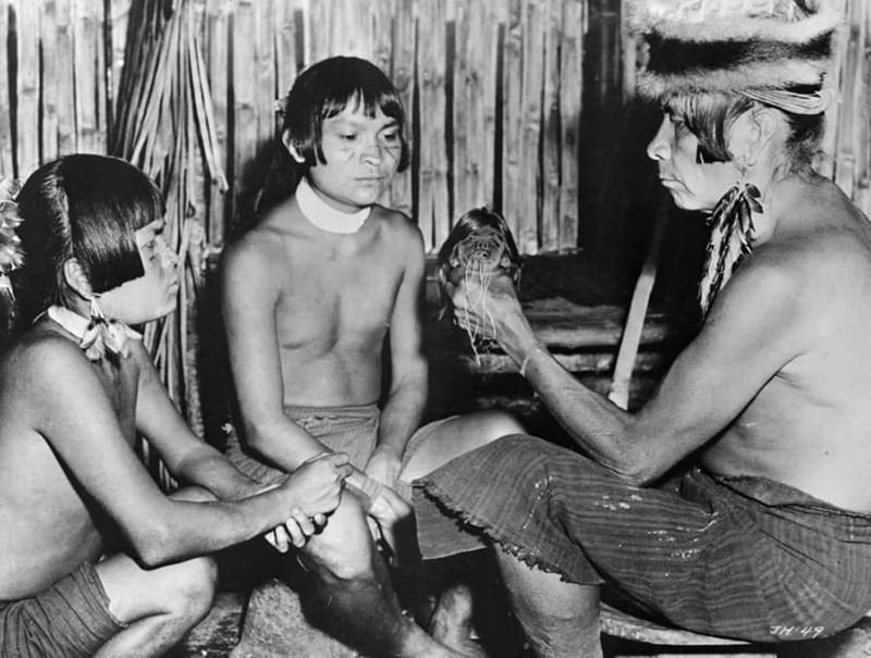A Jivaro priest is shown teaching the head shrinking ritual to the future successors of the tribe, via “All that’s Interesting”, 2018.
