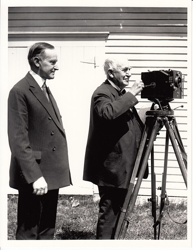Thomas Edison turning the crank of motion picture camera as President Calvin Coolidge looks on.