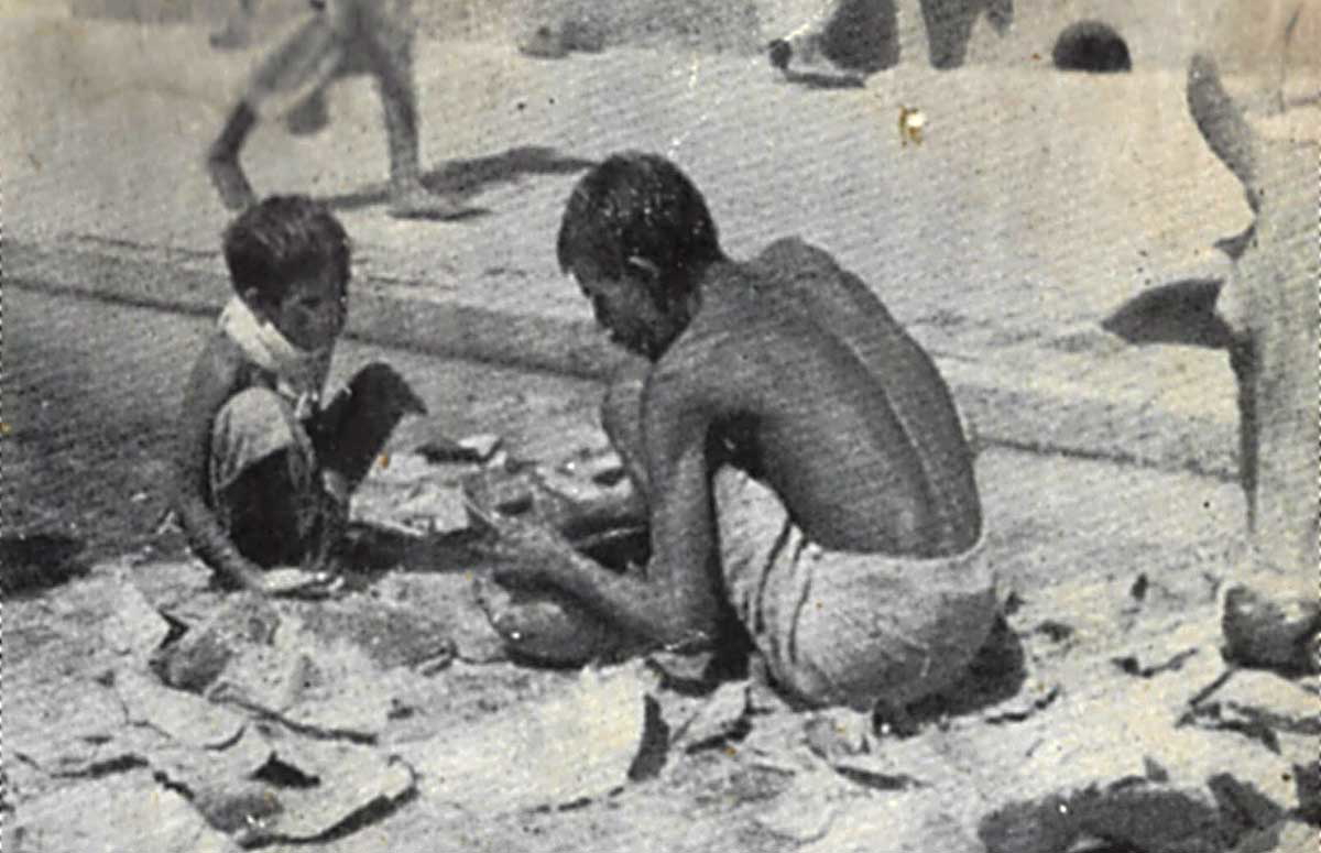 A father, his young son, and a cow rummaging for scraps of food on the street during the Bengal famine 1943