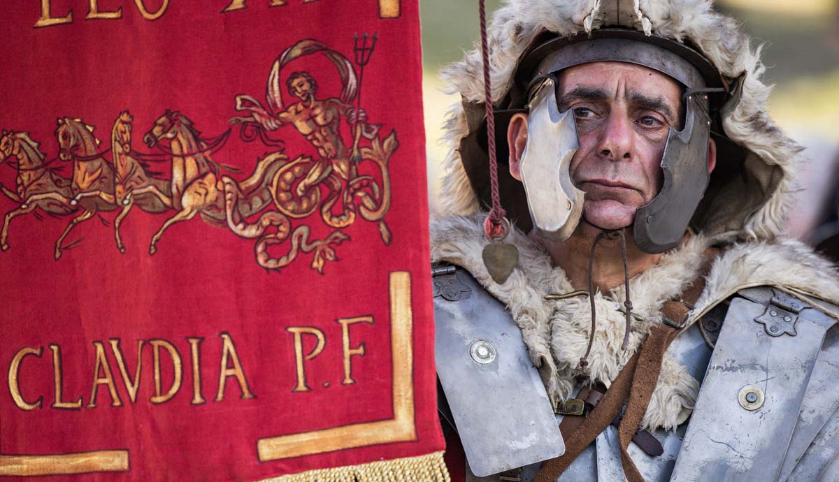 Roman reenactor in armor beside red standard
