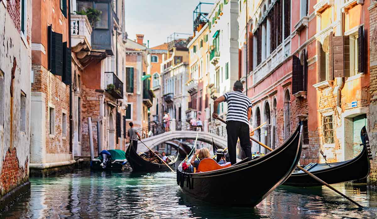 Gondolier rowing gondola on canal in Venice, Italy