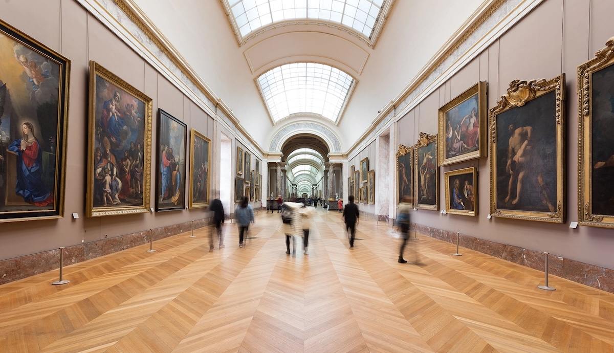 Interior of the Louvre Museum with visitors viewing famous European paintings