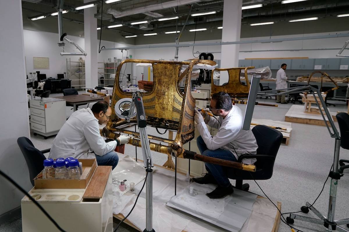 Conservators work on the restoration of a chariot from Tutankhamun's tomb in the Grand Egyptian Museum's conservation center
