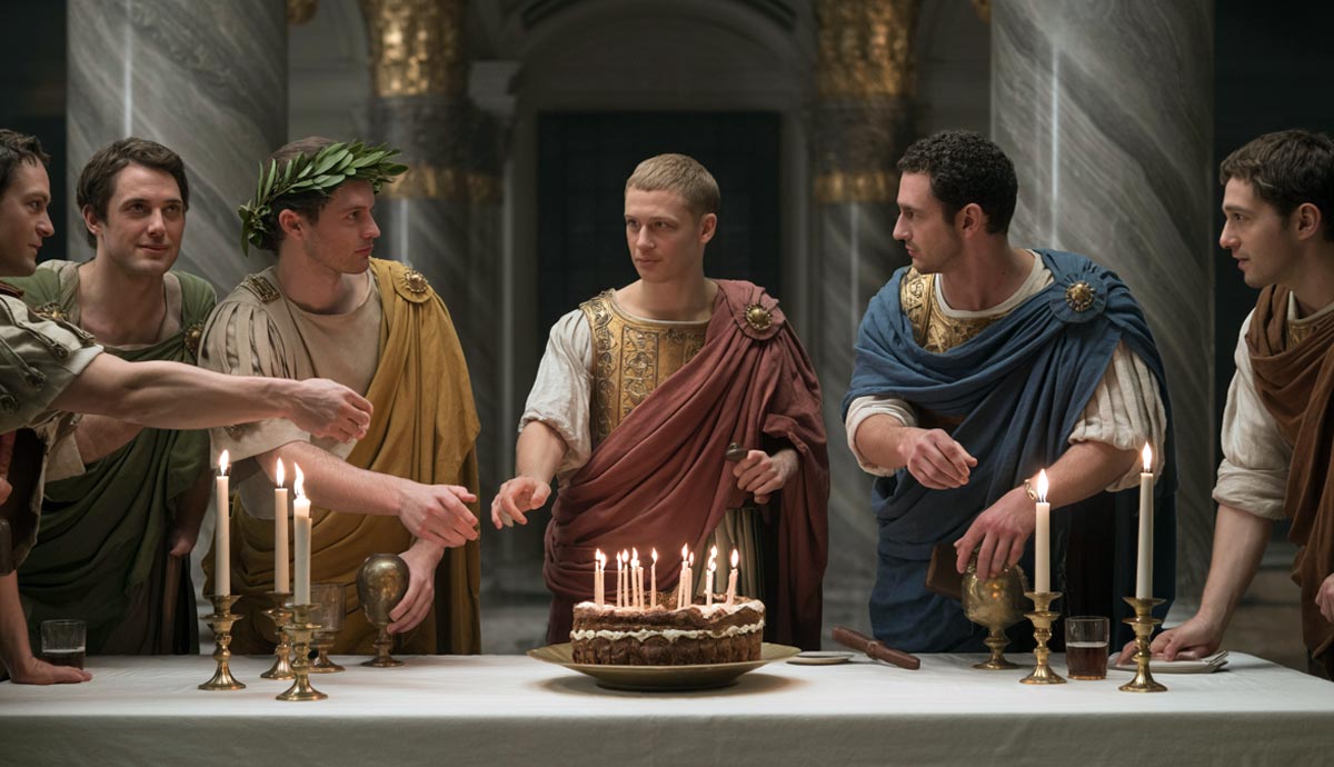 Men in Roman attire around a cake