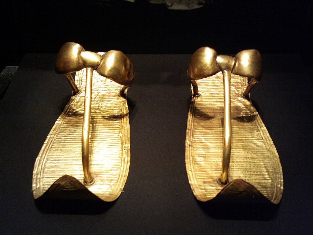 Close view of Tutankhamun’s gilded sandals on a display stand, gold sheets over leather
