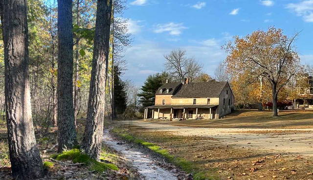 historic farmhouse beside autumn forest trail