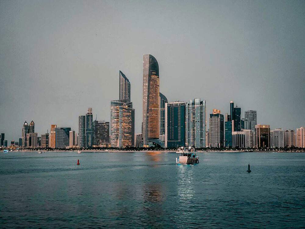 View of Abu Dhabi’s skyline and waterfront under soft afternoon light, showcasing modern skyscrapers and architecture.
