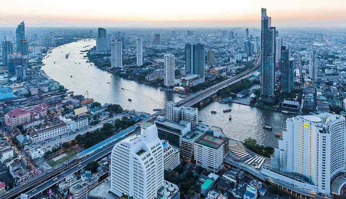 View of Bangkok’s Chao Phraya River with high-rise buildings and cityscape under a clear sky.