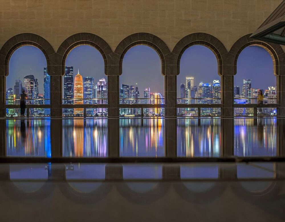 Exterior view of Doha’s Museum of Islamic Art on the waterfront, featuring geometric architecture and clear skies.