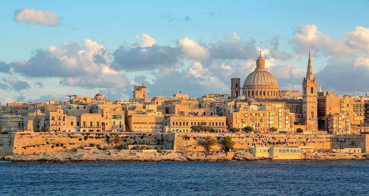 View of a historic stone building in Malta with ornate windows and architectural details.
