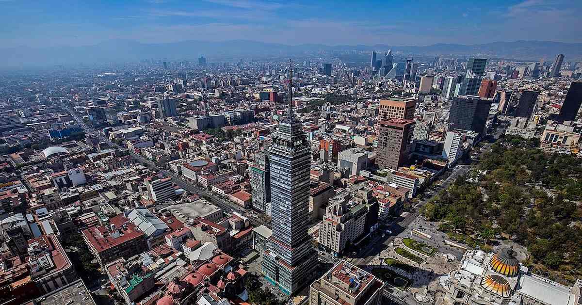 Aerial view of Mexico City showing urban buildings and streets under a bright sky.