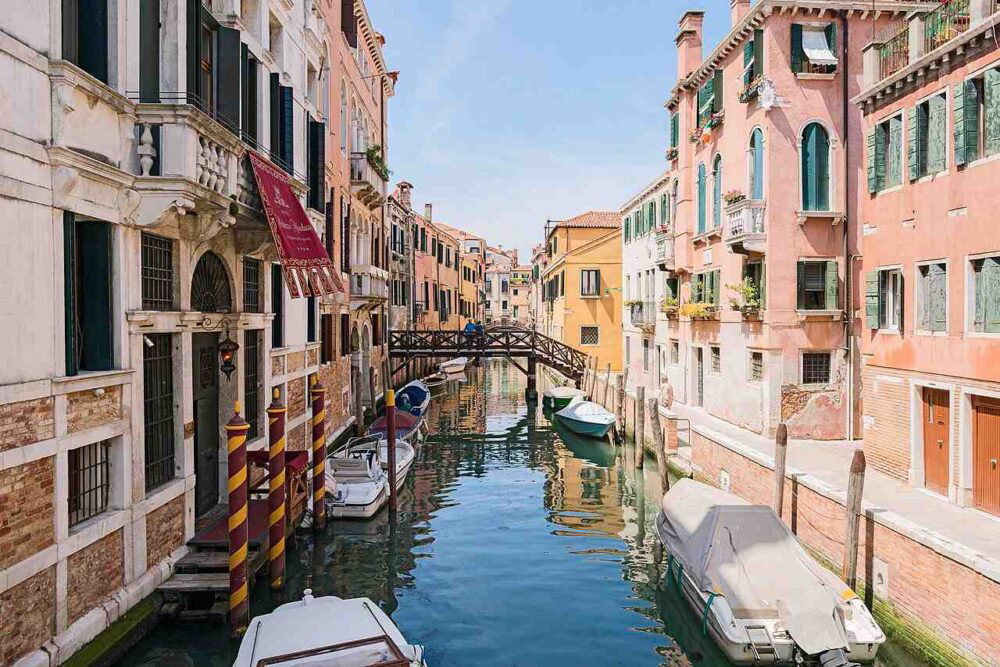 Canal in Venice, Italy, with colorful historic buildings lining the waterway under a cloudy sky.