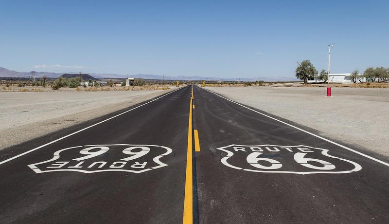 Wide view of historic Route 66 passing through Amboy, California, with Roy’s Motel and Café visible against the Mojave Desert backdrop
