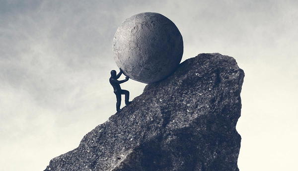 Man pushing large boulder up hill
