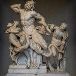 An ancient Greco-Roman marble statuary group featuring a muscular, bearded man—the priest Laocoön—and his two sons. They are entwined in the thick, writhing coils of two giant snakes. The father’s face is contorted in a visceral expression of agony, while the boys display terror and exhaustion as they are constricted.