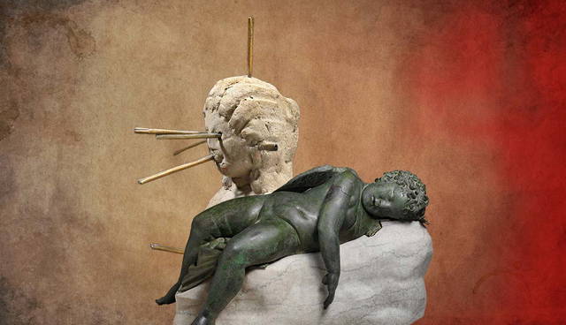 Stone sculptures of a head with pins and a sleeping Eros