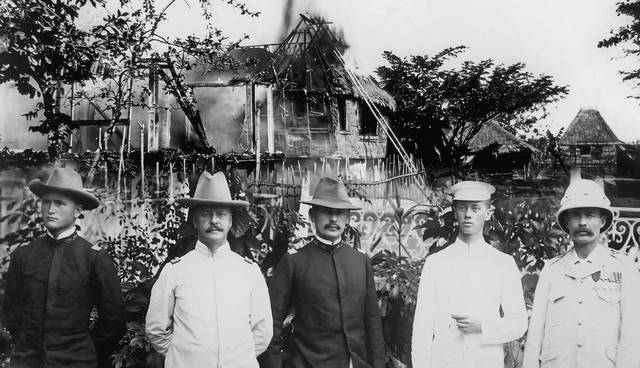 Five men in uniform before burning house