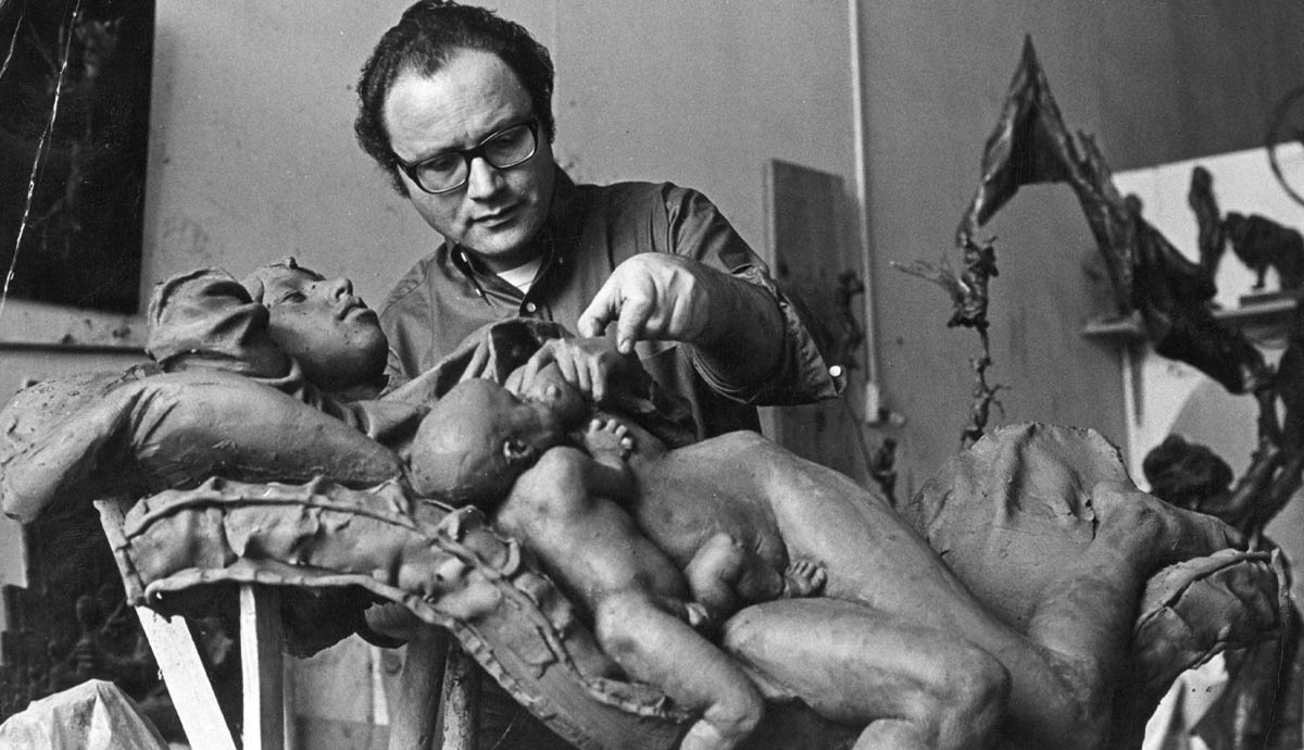 Man sculpting a clay figure in an art studio.