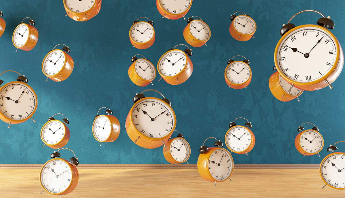 Orange alarm clocks floating against a teal wall.