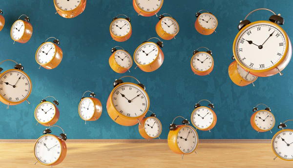 Orange alarm clocks floating against a teal wall.