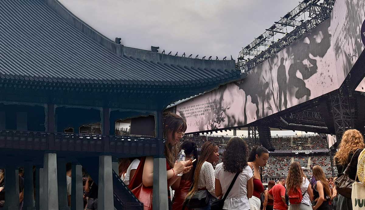 A crowded concert stadium with a traditional Asian roof structure.