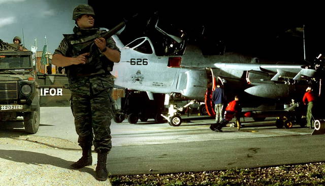 A soldier on guard beside a military aircraft.