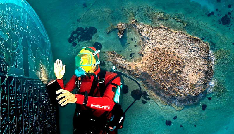 Scuba diver examining hieroglyphics next to an island.